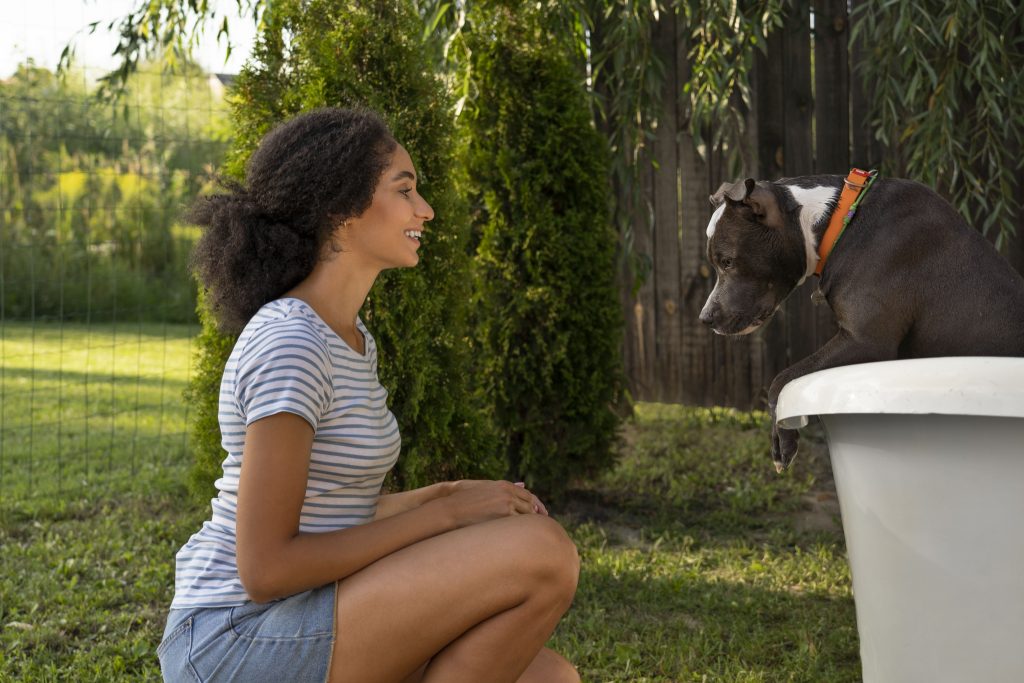 Tutora olhando para o cachorro dentro de uma banheira 